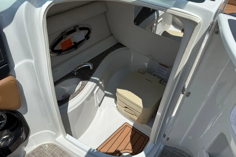 Slide: The Image of 2024 Crownline Eclipse E235 boat interior with compact bathroom and portable toilet. - 7