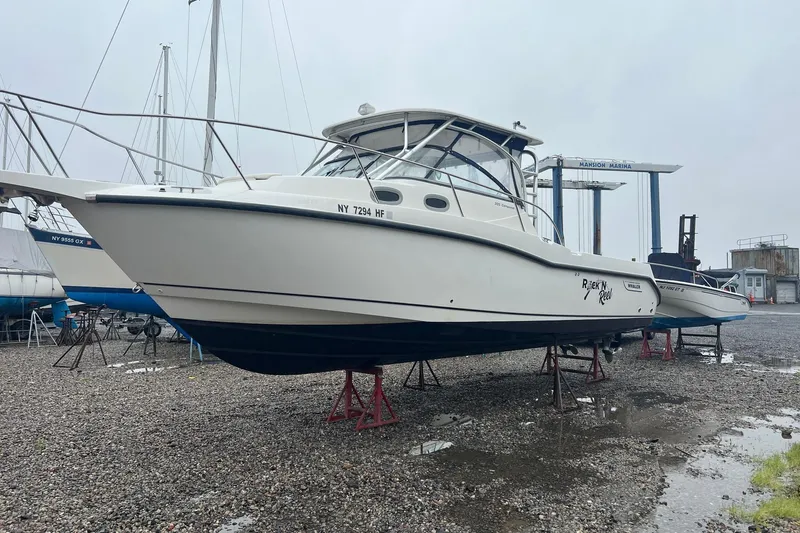 The Image of 2005 Boston Whaler 305 Conquest boat on stands at marina, overcast day. - 0