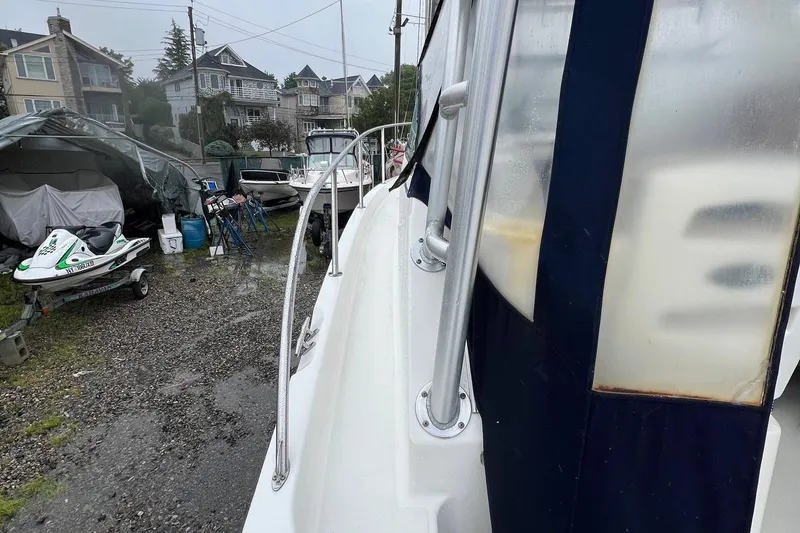 Slide: The Image of 2005 Boston Whaler 305 Conquest boat docked near residential area, with jet ski nearby. - 18