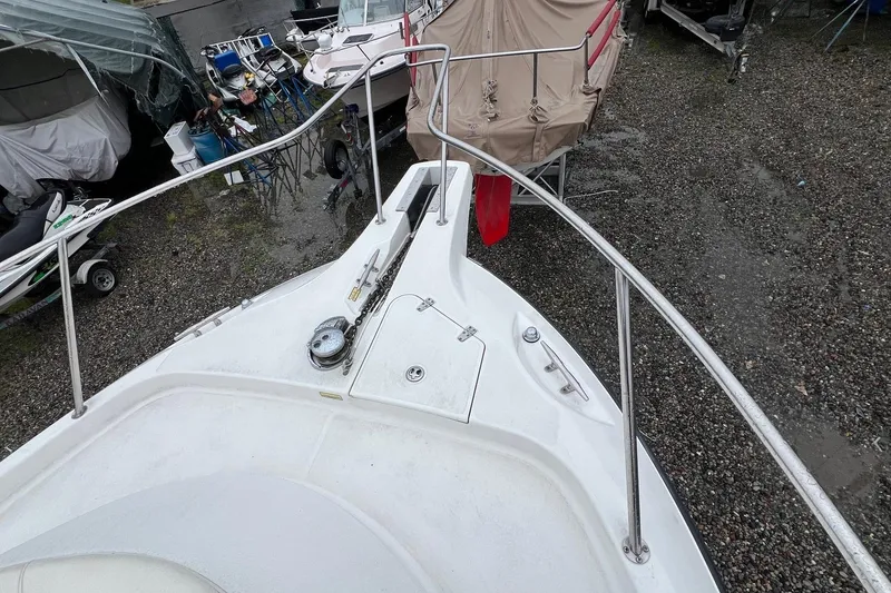 Slide: The Image of 2005 Boston Whaler 305 Conquest boat deck with railing, parked on gravel. - 19