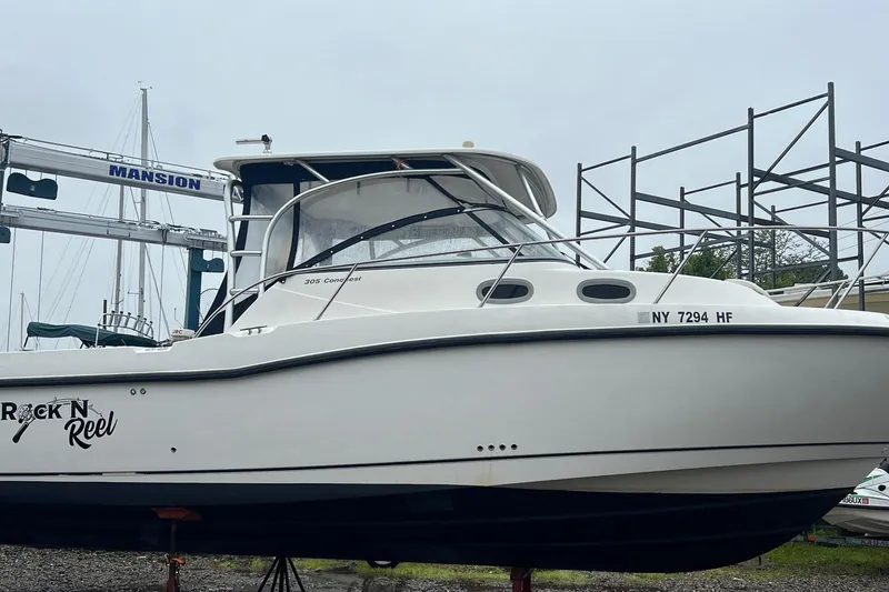 Slide: The Image of 2005 Boston Whaler 305 Conquest boat on land, named "Rock N Reel," with visible registration. - 2