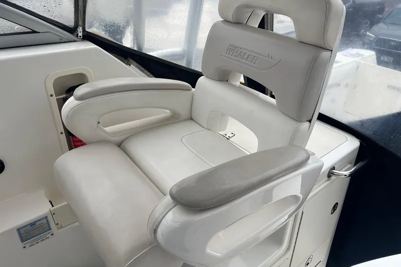 Slide: The Image of White captain's chair on 2005 Boston Whaler 305 Conquest boat, featuring armrests and logo. - 25