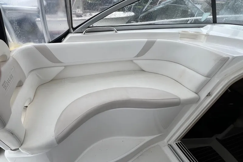 Slide: The Image of 2005 Boston Whaler 305 Conquest interior seating, featuring white cushioned bench. - 26