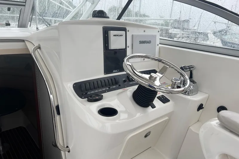 Slide: The Image of 2005 Boston Whaler 305 Conquest helm with steering wheel and navigation controls. - 28