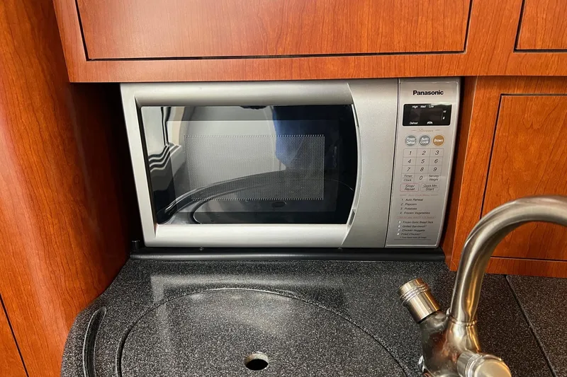 Slide: The Image of Microwave in 2005 Boston Whaler 305 Conquest kitchen with wood cabinetry and sink. - 41