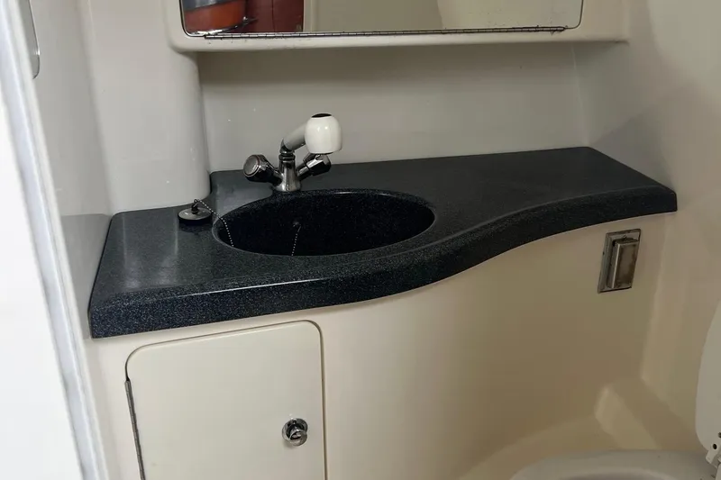 Slide: The Image of 2005 Boston Whaler 305 Conquest bathroom sink with dark countertop and mirror. - 43