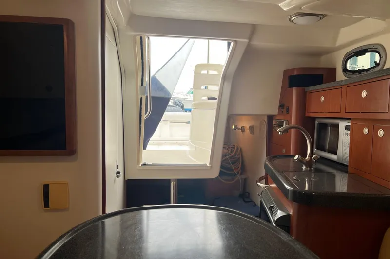 Slide: The Image of Interior of 2005 Boston Whaler 305 Conquest boat, featuring kitchenette and seating area. - 44