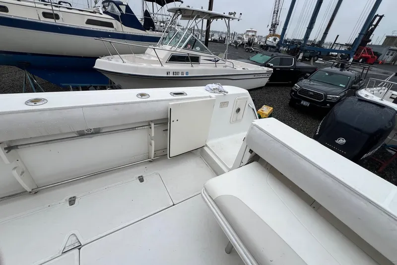 Slide: The Image of 2005 Boston Whaler 305 Conquest boat interior, docked with other vessels and vehicles nearby. - 9