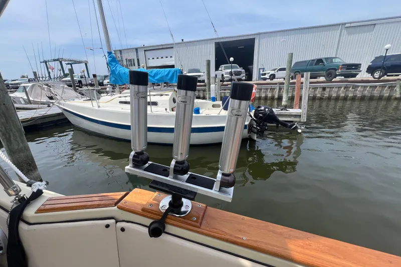 Slide: The Image of 1986 Sea Ray 270 Amberjack with rod holders, docked near sailboats and vehicles. - 13