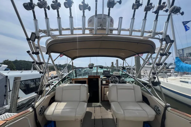 Slide: The Image of 1986 Sea Ray 270 Amberjack boat interior with fishing rod holders and seating at a marina. - 14