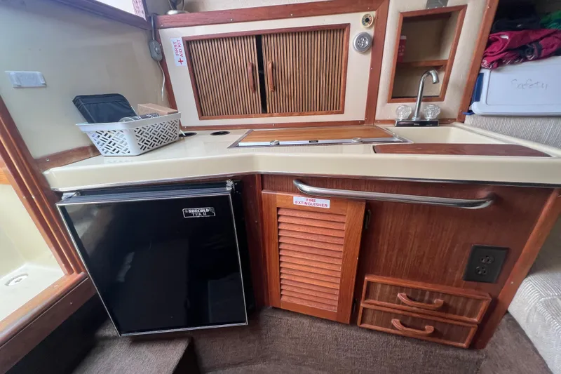 Slide: The Image of 1986 Sea Ray 270 Amberjack boat interior kitchen with sink, fridge, and storage cabinets. - 28