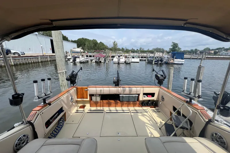 Slide: The Image of 1986 Sea Ray 270 Amberjack boat interior with fishing rod holders, docked at a marina. - 8