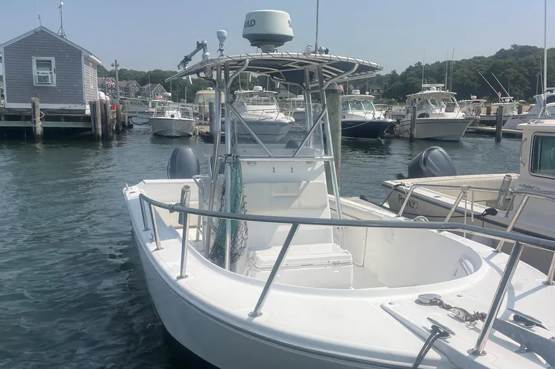 Slide: The Image of 2002 Edgewater 247CC boat docked in a marina, surrounded by other vessels. - 1