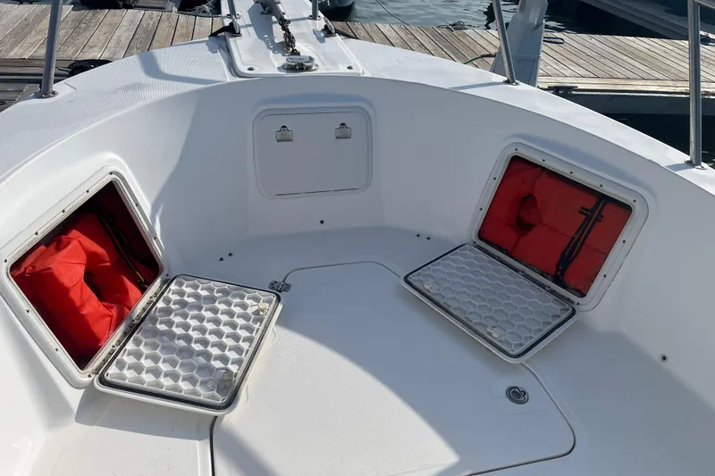 Slide: The Image of 2002 Edgewater 247CC boat storage compartments with red life jackets on deck. - 4