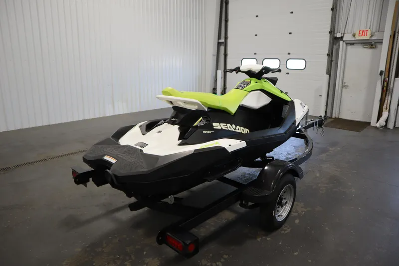 Slide: The Image of 2023 Sea-Doo Spark 3up jet ski with lime green seat on a trailer in a garage. - 5