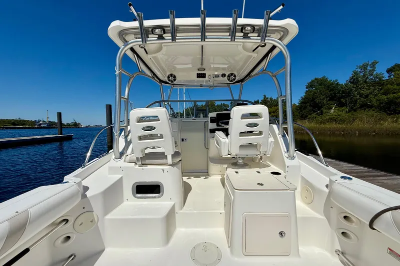 Slide: The Image of 2007 Boston Whaler 285 Conquest boat interior with seating and helm, docked by the water. - 13