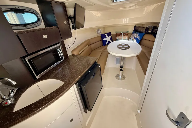 Slide: The Image of 2007 Boston Whaler 285 Conquest cabin interior with kitchenette, seating, and table. - 19