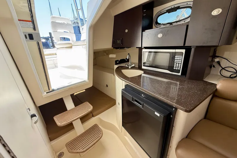 Slide: The Image of 2007 Boston Whaler 285 Conquest cabin interior with kitchenette, microwave, and seating. - 21