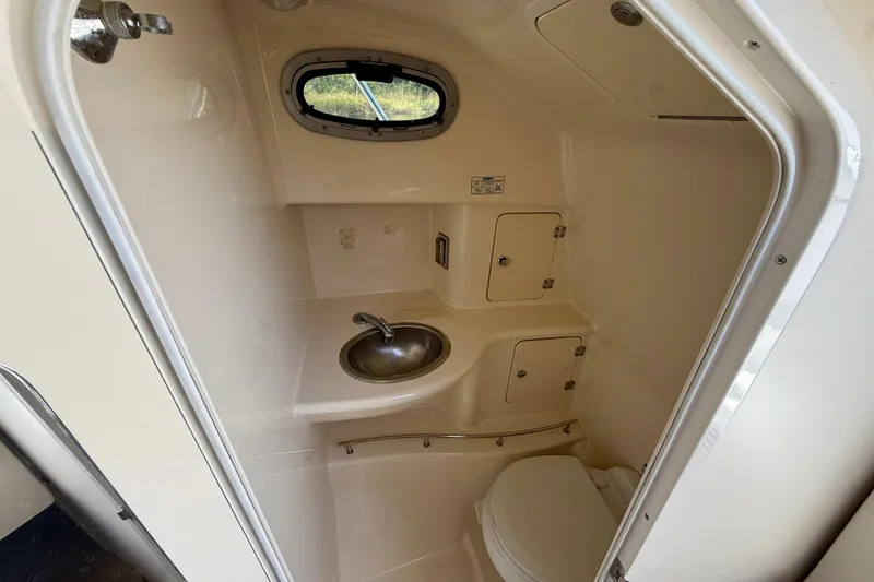 Slide: The Image of 2007 Boston Whaler 285 Conquest boat bathroom with sink, toilet, and storage compartments. - 22
