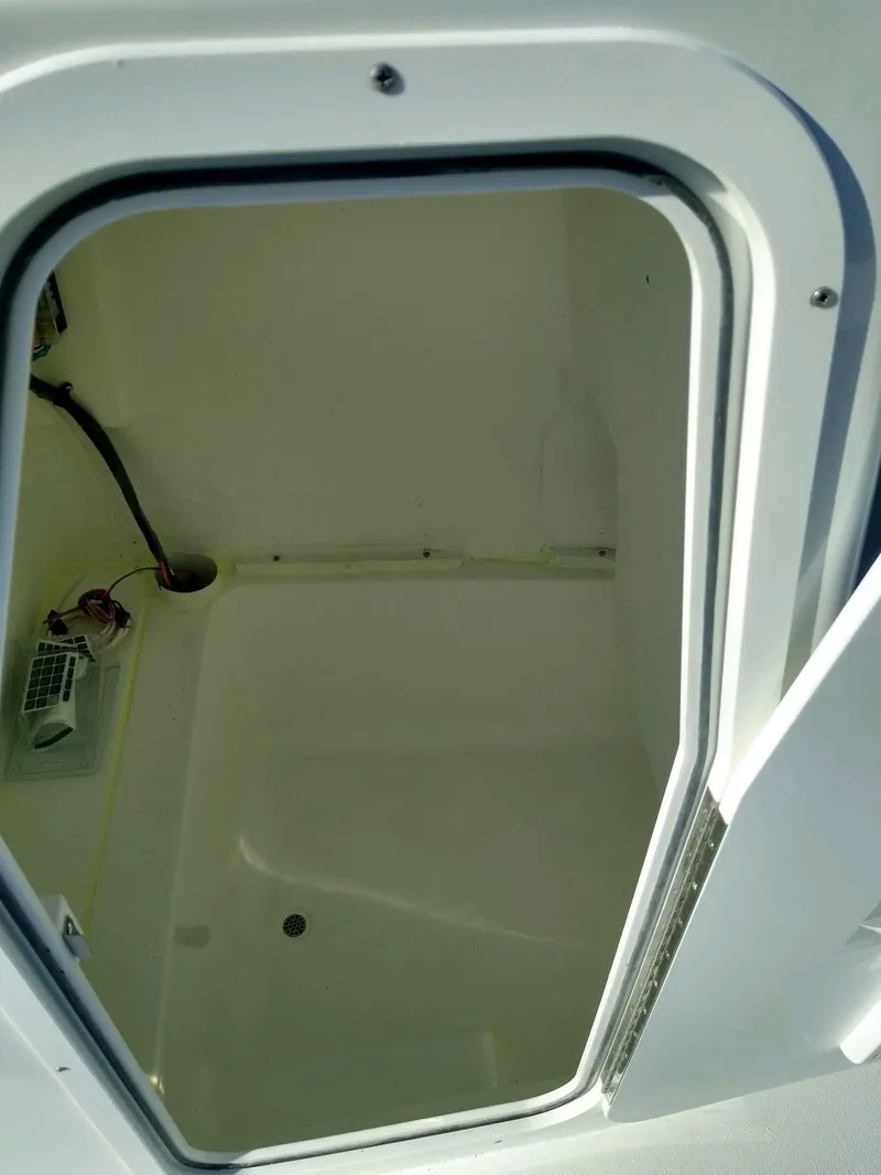Slide: The Image of 2024 Lookout Skiff 23CC storage compartment, open and empty, with visible wiring. - 6