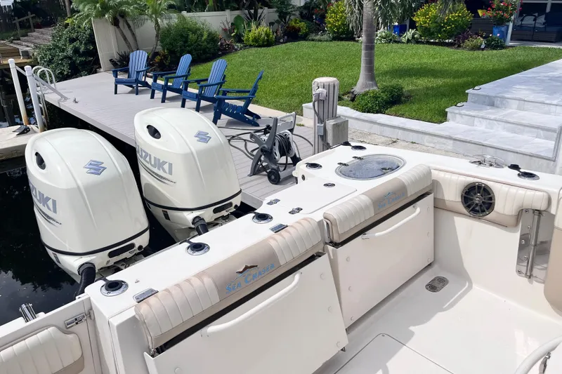 Slide: The Image of 2019 Sea Chaser 27 HFC boat with twin Suzuki outboard motors docked by a lush garden. - 17