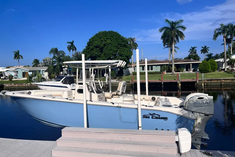 Slide: The Image of 2019 Sea Chaser 27 HFC boat docked by waterfront homes, under clear blue sky. - 2