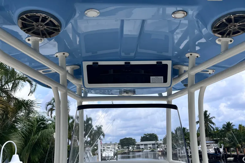 Slide: The Image of 2019 Sea Chaser 27 HFC boat interior with blue ceiling and speakers, docked near palm trees. - 6