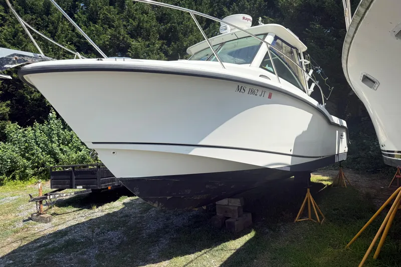 Slide: The Image of 2014 Boston Whaler 285 Conquest boat on stands, surrounded by trees. - 3