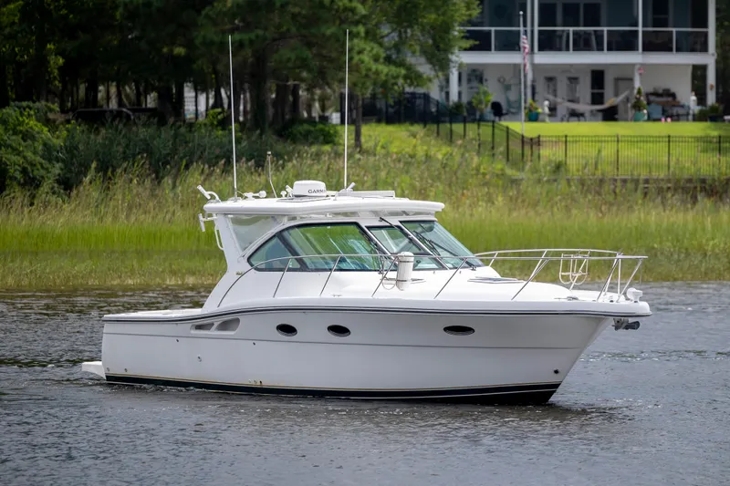 The Image of 2004 Tiara Yachts 3200 Open cruising on a serene waterway near a lush shoreline. - 0