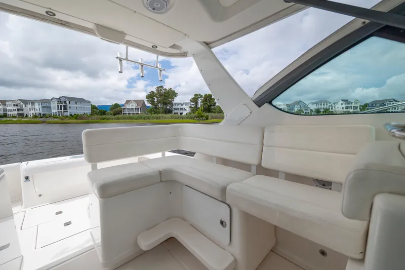Slide: The Image of 2004 Tiara Yachts 3200 Open interior with white seating, overlooking waterfront homes. - 21