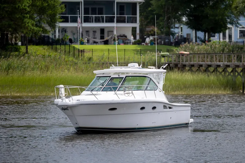 Slide: The Image of 2004 Tiara Yachts 3200 Open cruising on a serene river near waterfront homes. - 3