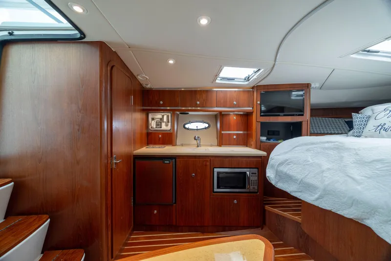 Slide: The Image of 2004 Tiara Yachts 3200 Open interior with kitchenette, bed, and wooden cabinetry. - 30