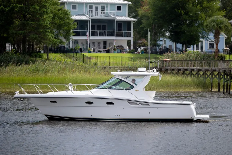 Slide: The Image of 2004 Tiara Yachts 3200 Open cruising on a serene river near waterfront homes. - 4