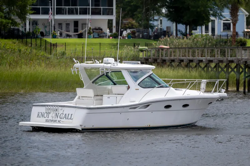Slide: The Image of 2004 Tiara Yachts 3200 Open boat named "Knot on Call" on a serene waterway. - 7