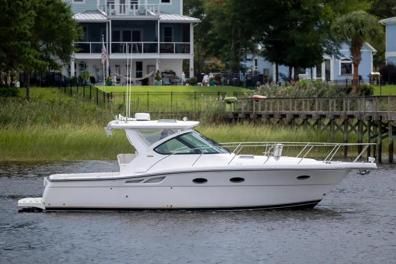 Slide: The Image of 2004 Tiara Yachts 3200 Open cruising on a serene waterfront near houses. - 8