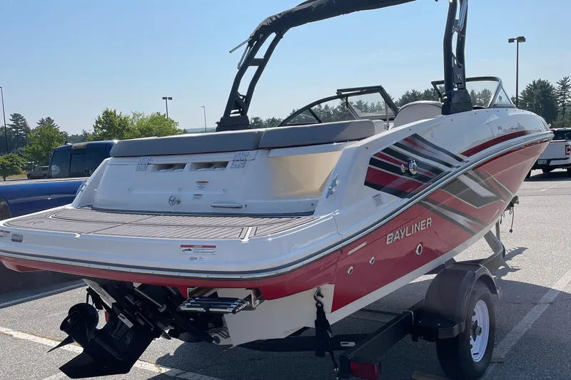 Slide: The Image of 2024 Bayliner VR5 Bowrider I/O boat with red and white design in a parking lot. - 3