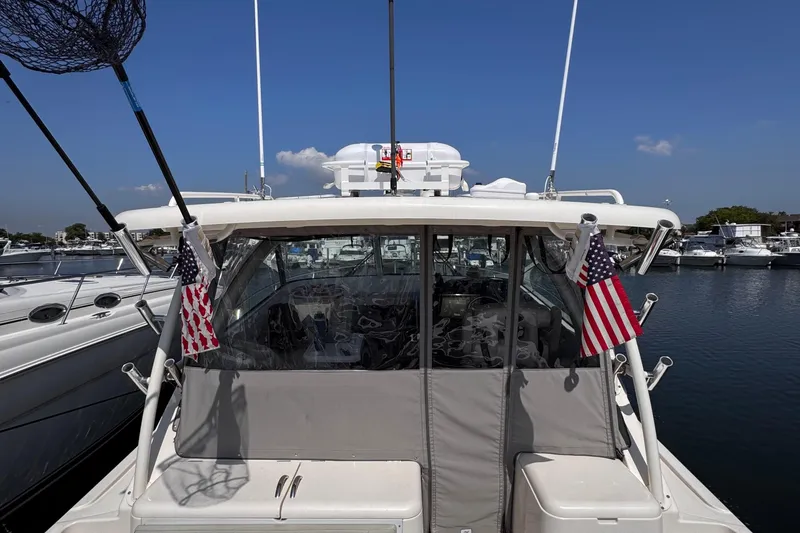 Slide: The Image of 2011 Pursuit OS 345 Offshore boat docked, featuring American flags and fishing equipment. - 12
