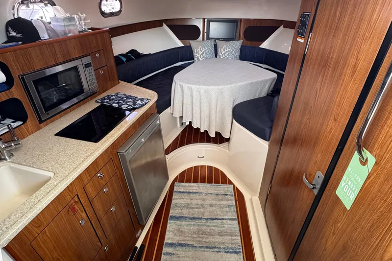 Slide: The Image of 2011 Pursuit OS 345 Offshore cabin interior with kitchenette and cozy seating area. - 18