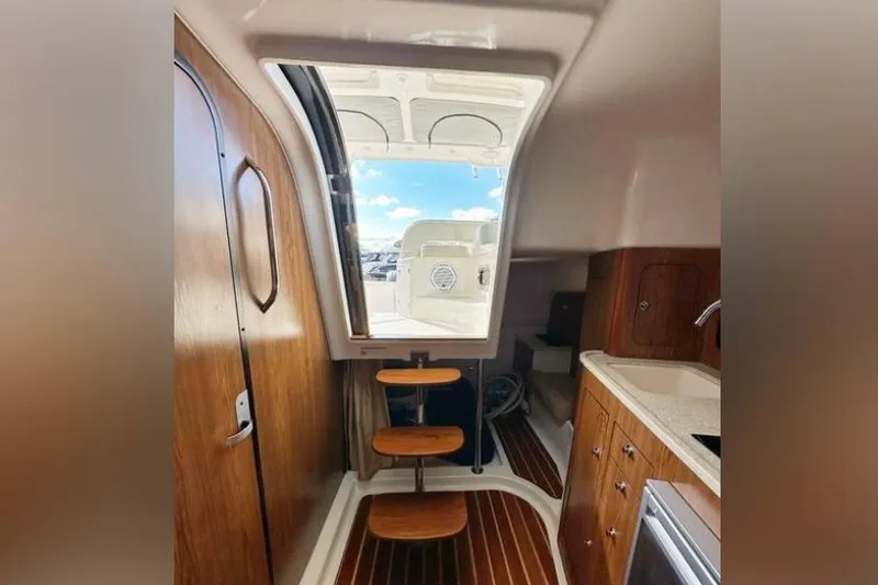 Slide: The Image of Interior of 2011 Pursuit OS 345 Offshore boat, featuring wooden cabinetry and steps. - 29