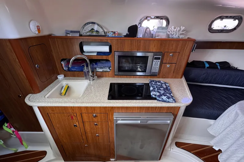 Slide: The Image of Compact kitchen area in a 2011 Pursuit OS 345 Offshore boat with sink, microwave, and stove. - 39