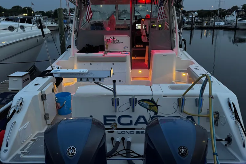 Slide: The Image of 2011 Pursuit OS 345 Offshore boat docked, illuminated interior, dual Yamaha engines, evening setting. - 7