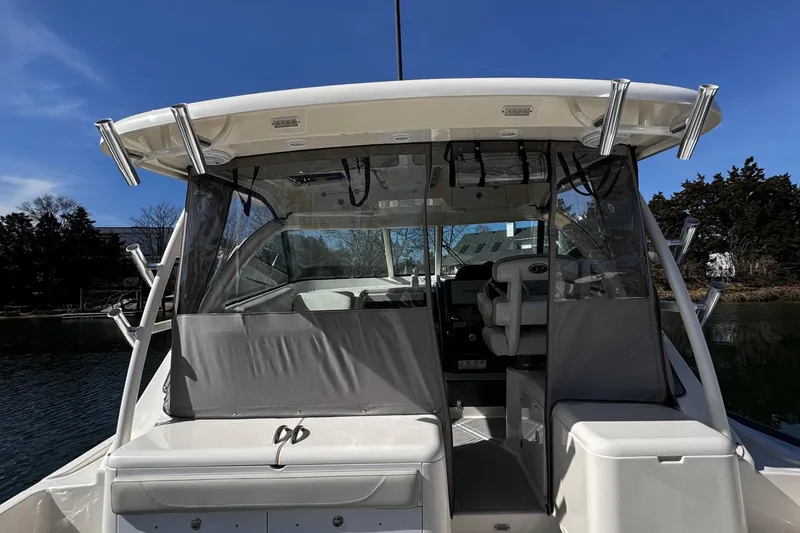 Slide: The Image of 2011 Pursuit OS 345 Offshore boat with covered cockpit and rod holders, docked on a sunny day. - 8