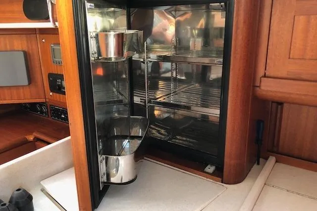 Slide: The Image of Interior of 1999 Sweden Yachts 45, featuring a compact kitchen fridge with wooden cabinetry. - 22