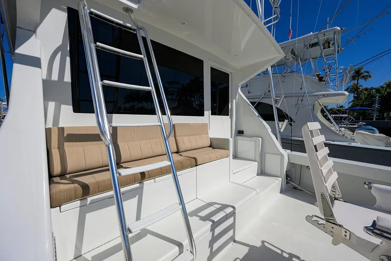 Slide: The Image of 1998 Viking 53 Convertible yacht deck with seating and ladder under clear blue sky. - 13