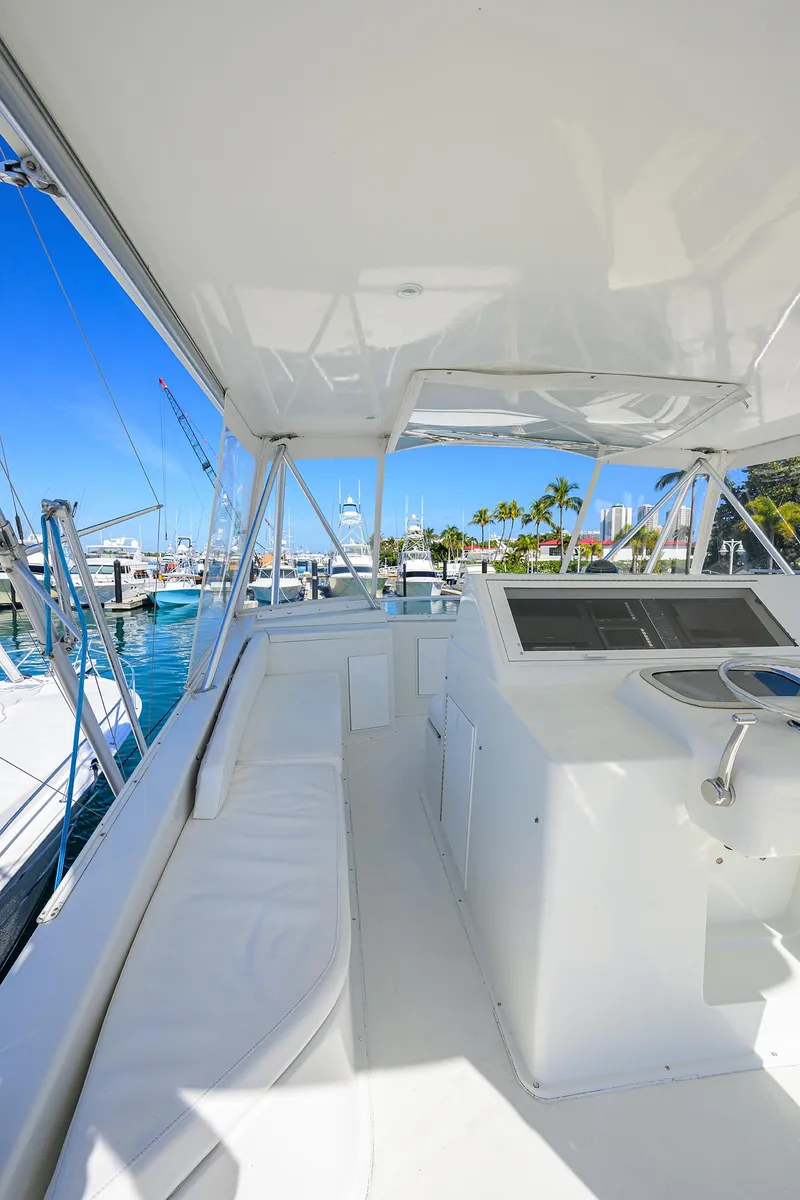Slide: The Image of 1998 Viking 53 Convertible yacht interior with helm, white seating, and marina view. - 45