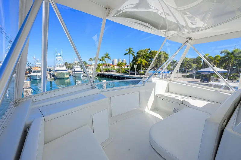 Slide: The Image of 1998 Viking 53 Convertible yacht interior with marina view, featuring white seating and clear windows. - 46