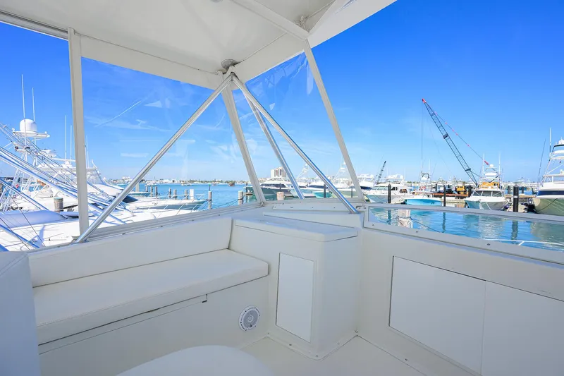 Slide: The Image of 1998 Viking 53 Convertible yacht interior with marina view, featuring white seating and clear windows. - 48