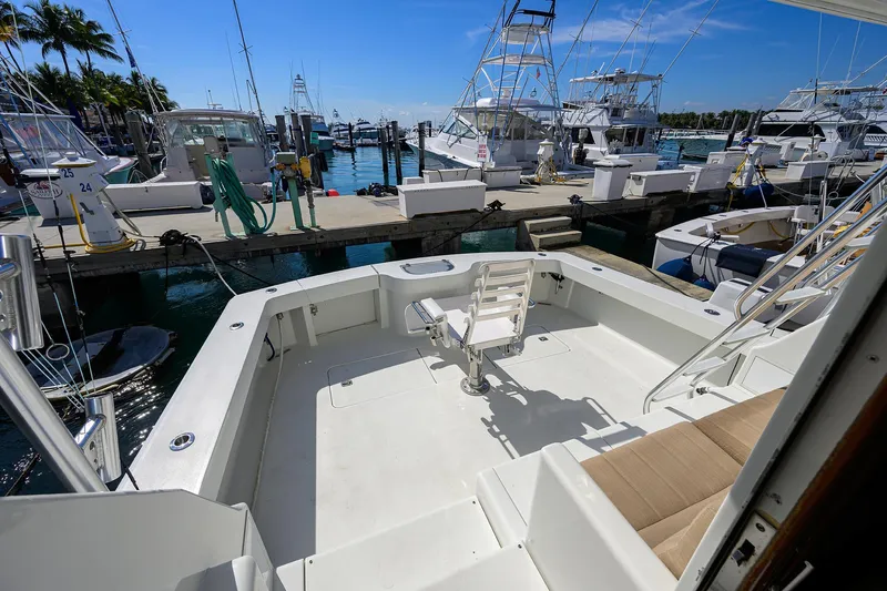 Slide: The Image of 1998 Viking 53 Convertible yacht docked at marina, featuring spacious deck and fishing chair. - 8