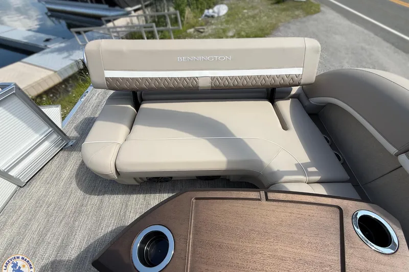 Slide: The Image of 2025 Bennington 22ML boat interior with beige seating and wooden table. - 15