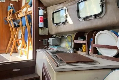 Slide: The Image of Interior of 1985 Albin 27 Family boat showing compact kitchen area with sink and storage. - 15